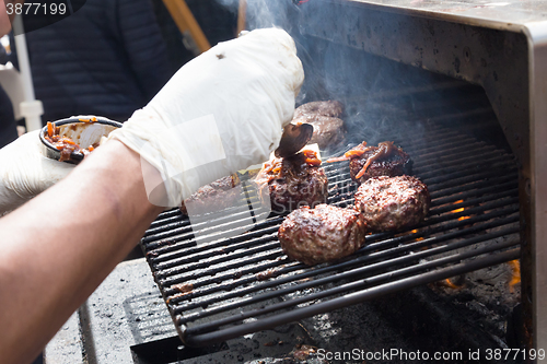 Image of Beef burgers being grilled on food stall grill.