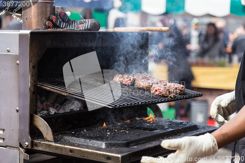 Image of Beef burgers being grilled on food stall grill.