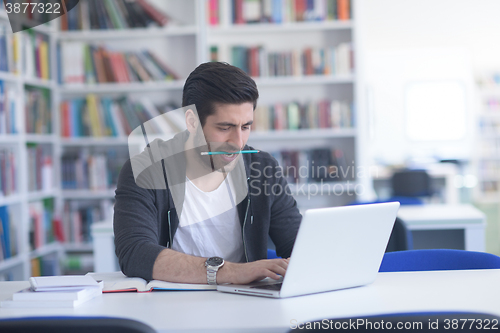Image of student in school library using laptop for research