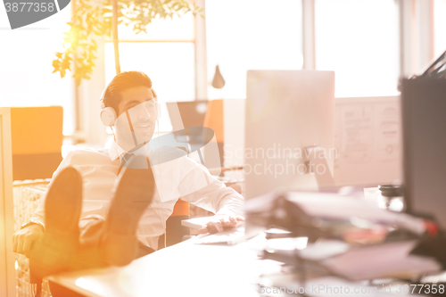 Image of relaxed young businessman first at workplace at early morning