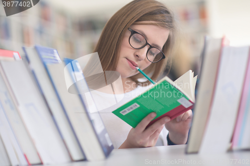 Image of portrait of famale student selecting book to read in library