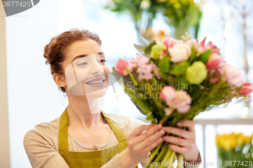 Image of smiling florist woman making bunch at flower shop