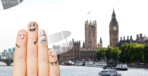 Image of close up of fingers with smiley faces over london