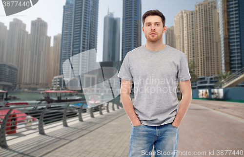 Image of young man in gray t-shirt and jeans over city 