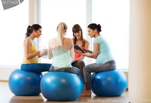 Image of happy pregnant women with gadgets in gym