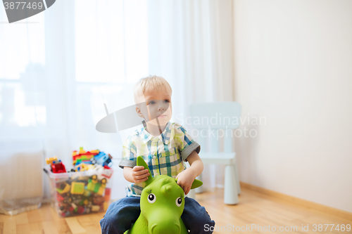 Image of happy baby boy playing with ride-on toy at home