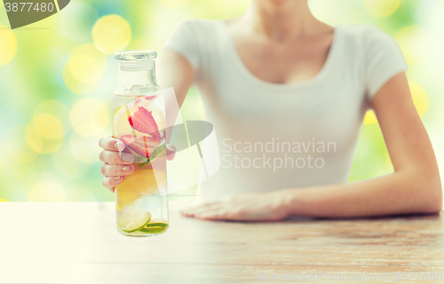 Image of close up of woman with fruit water in glass bottle