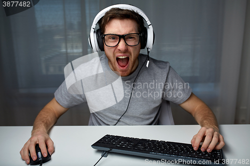 Image of man in headset playing computer video game at home