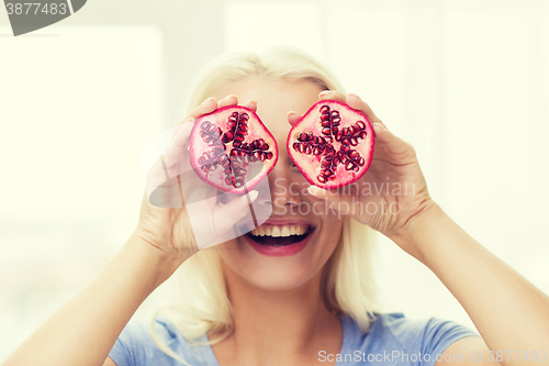 Image of happy woman covering eyes with pomegranate