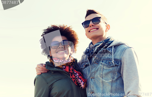 Image of happy teenage friends in shades hugging outdoors