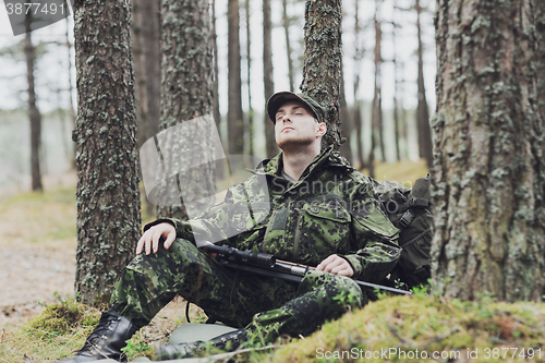 Image of soldier or hunter with gun sleeping in forest