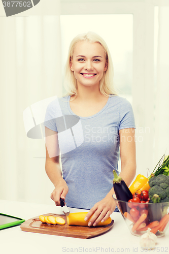 Image of smiling young woman chopping vegetables at home