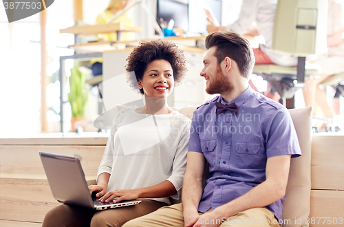 Image of happy creative team with laptop in office