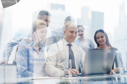 Image of smiling business people with laptop in office