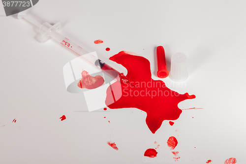 Image of Syringe Squirting Red Blood onto White Background