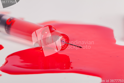 Image of Syringe Squirting Red Blood onto White Background