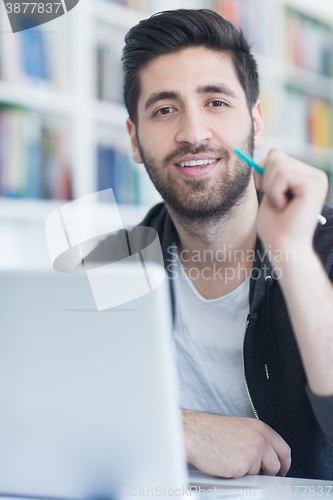 Image of student in school library using laptop for research