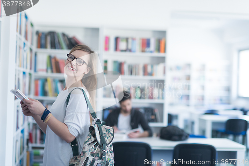 Image of famale student selecting book to read in library