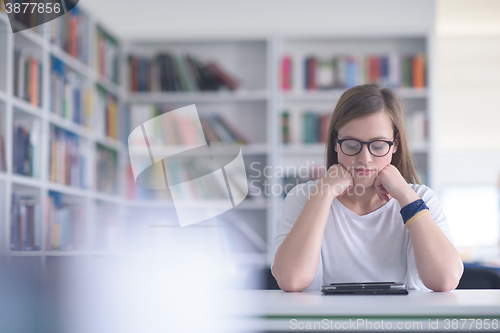 Image of female student study in school library, using tablet