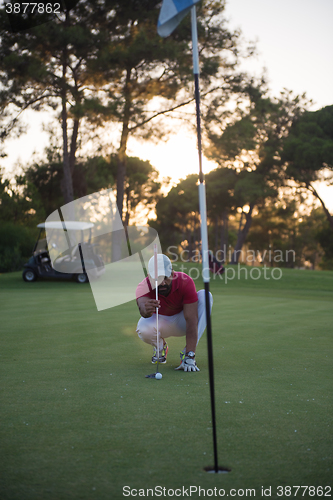 Image of golf player aiming perfect  shot on beautiful sunset