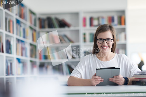 Image of female student study in school library, using tablet