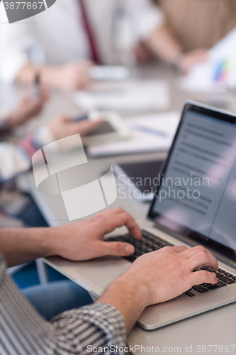 Image of close up of business man hands typing on laptop with team on mee