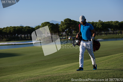 Image of golf player walking and carrying bag