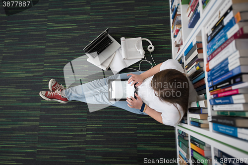 Image of female student study in library, using tablet and searching for 