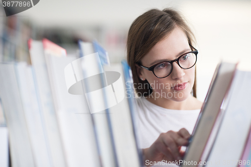 Image of portrait of famale student selecting book to read in library