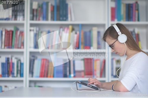 Image of female student study in library, using tablet and searching for 