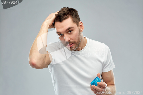 Image of happy young man styling his hair with wax or gel