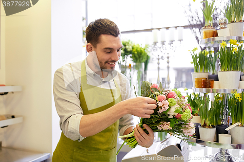 Image of smiling florist man making bunch at flower shop