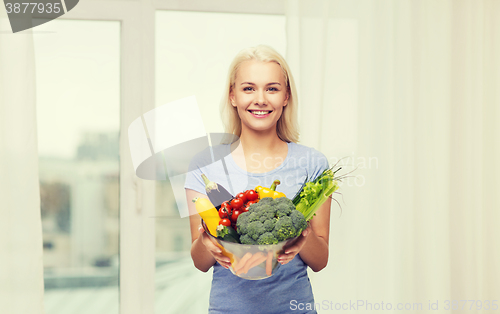 Image of smiling young woman with vegetables at home