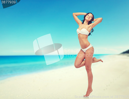 Image of happy young woman in white bikini swimsuit