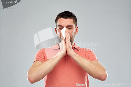 Image of sick man with paper napkin blowing nose