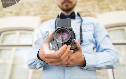 Image of close up of hipster man with film camera in city