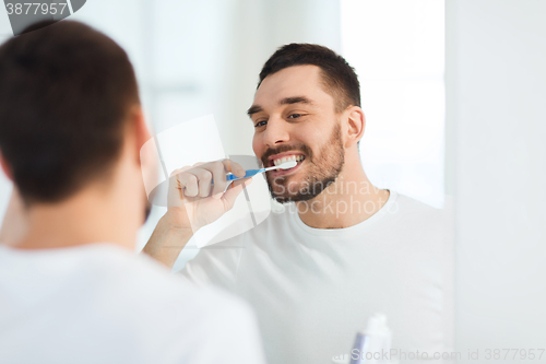 Image of man with toothbrush cleaning teeth at bathroom
