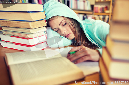 Image of student or woman with books sleeping in library