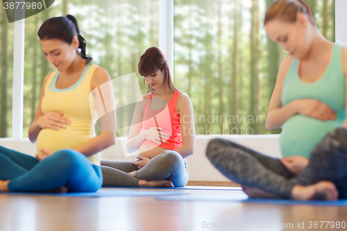 Image of happy pregnant women exercising yoga in gym