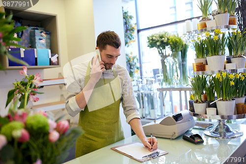 Image of man with smartphone making notes at flower shop