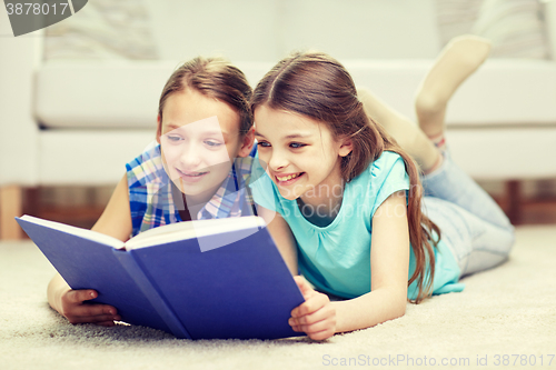 Image of two happy girls reading book at home