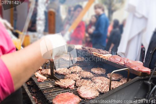 Image of Beef burgers being grilled on food stall grill.