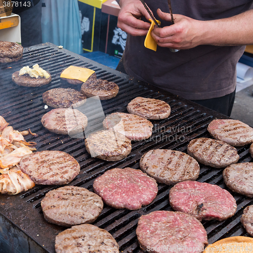 Image of Beef burgers being grilled on food stall grill.