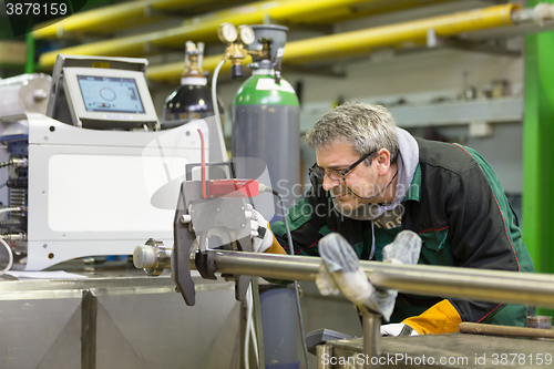 Image of Industrial worker setting orbital welding machine.