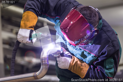 Image of Industrial worker welding in metal factory.