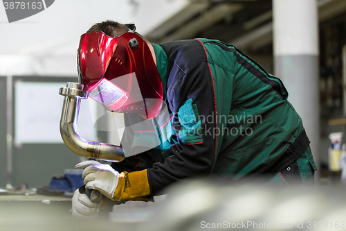 Image of Industrial worker welding in metal factory.