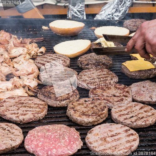 Image of Beef burgers being grilled on food stall grill.