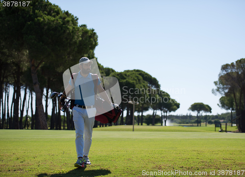 Image of golf player walking and carrying bag