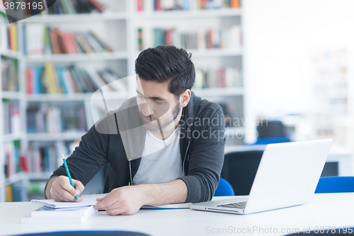 Image of student in school library using laptop for research