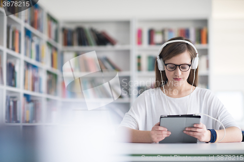 Image of female student study in library, using tablet and searching for 